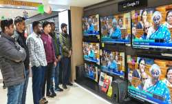 टीवी की दुकान पर रविवार को बजट भाषण सुनते लोग।- India TV Paisa