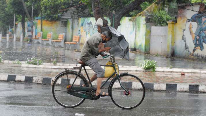 A cyclist holding an umbrella rides through wind and rain ahead of the landfall of cyclone Amphan, i