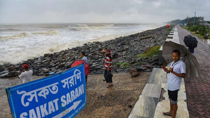 People watch as waves crash along the shore of Talasari Beach as super cyclone Amphan makes its land