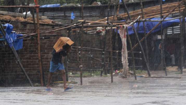 A man covers him head with a box and walks in the rain ahead of Cyclone Amphan landfall, at Bhadrak 
