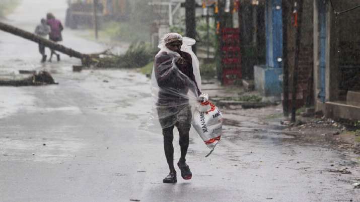 A man covers himself with a plastic sheet and walks in the rain ahead of Cyclone Amphan landfall, at