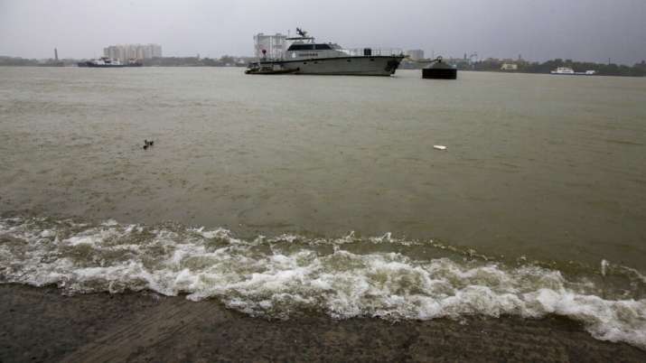 Water waves break on the banks of Hooghly River as an Indian Customs department ship is moored in th