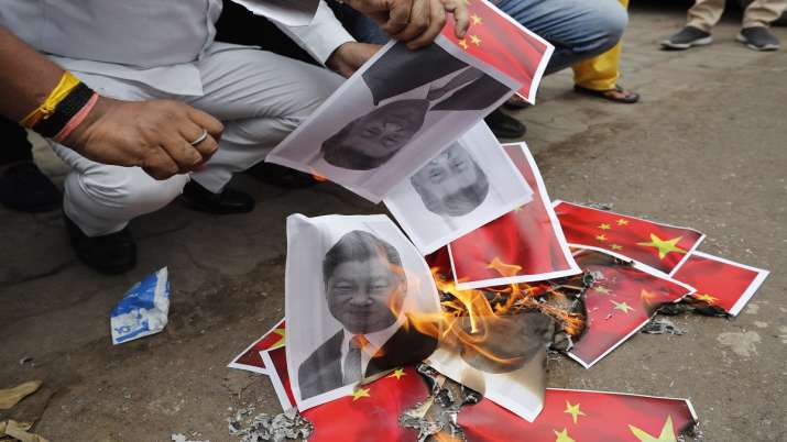 Indians burn photographs of Chinese President Xi Jinping during a protest against the Chinese govern