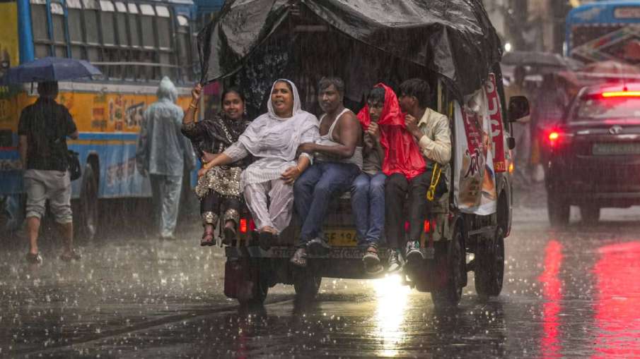 कोलकाता में बारिश के बीच जाते लोग