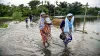 People wade through a flooded road following the incessant monsoon rainfalls at Kalgachi, in Barpeta- India TV Hindi