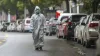 A medical worker in protective gear walks in the street...- India TV Hindi