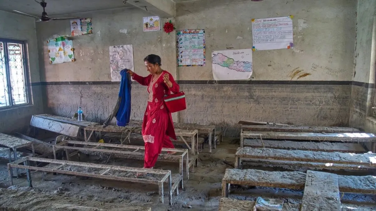 नेपाल के धादिंग जिले के गलछी स्थित श्री बागेश्वरी माध्यमिक स्कूल में एक छात्र की मां बाढ़ से क्षतिग्रस्त कक्षा के अंदर बच्चे का सामान तलाश रही है। कमरे में भरपूर कीचड़ और मलबा जमा है।