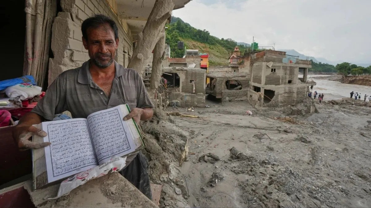 नेपाल के नुवाकोट जिले के देवीघाट में एक निवासी अपने क्षतिग्रस्त और कीचड़ से भरे घर से सामान निकालते हुए पवित्र धार्मिक पुस्तक दिखाता है। बाढ़ के बाद घर का काफी हिस्सा मलबे में बदल गया है।