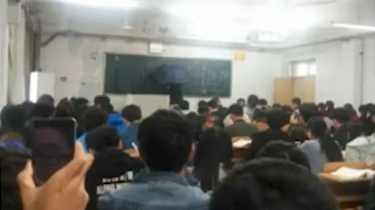 Chinese teacher gives lesson in a classroom with umbrella due to leakage | YouTube Grab- India TV Hindi