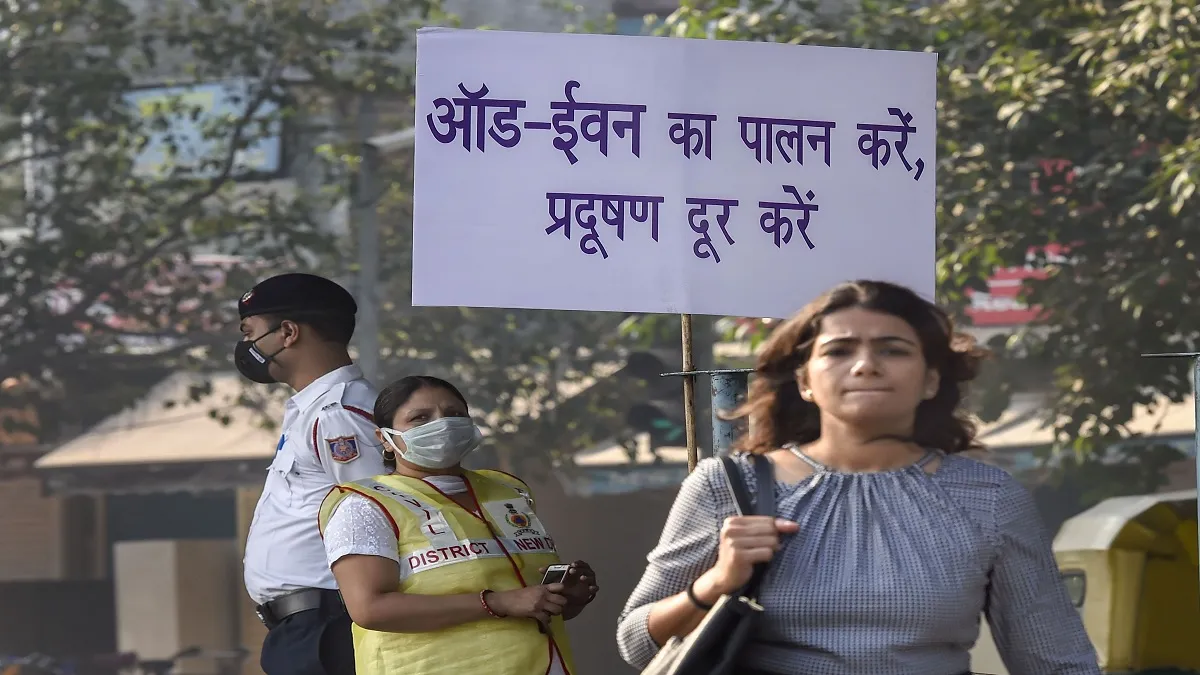 Civil Defence volunteer wearing a mask displays a placard asking people to obey the odd-even rule, i- India TV Paisa