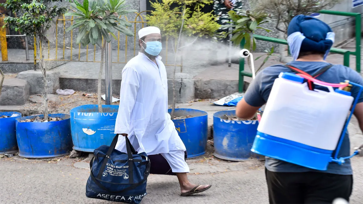 New Delhi: A volunteer sprays disinfectant on a masked man...- India TV Hindi