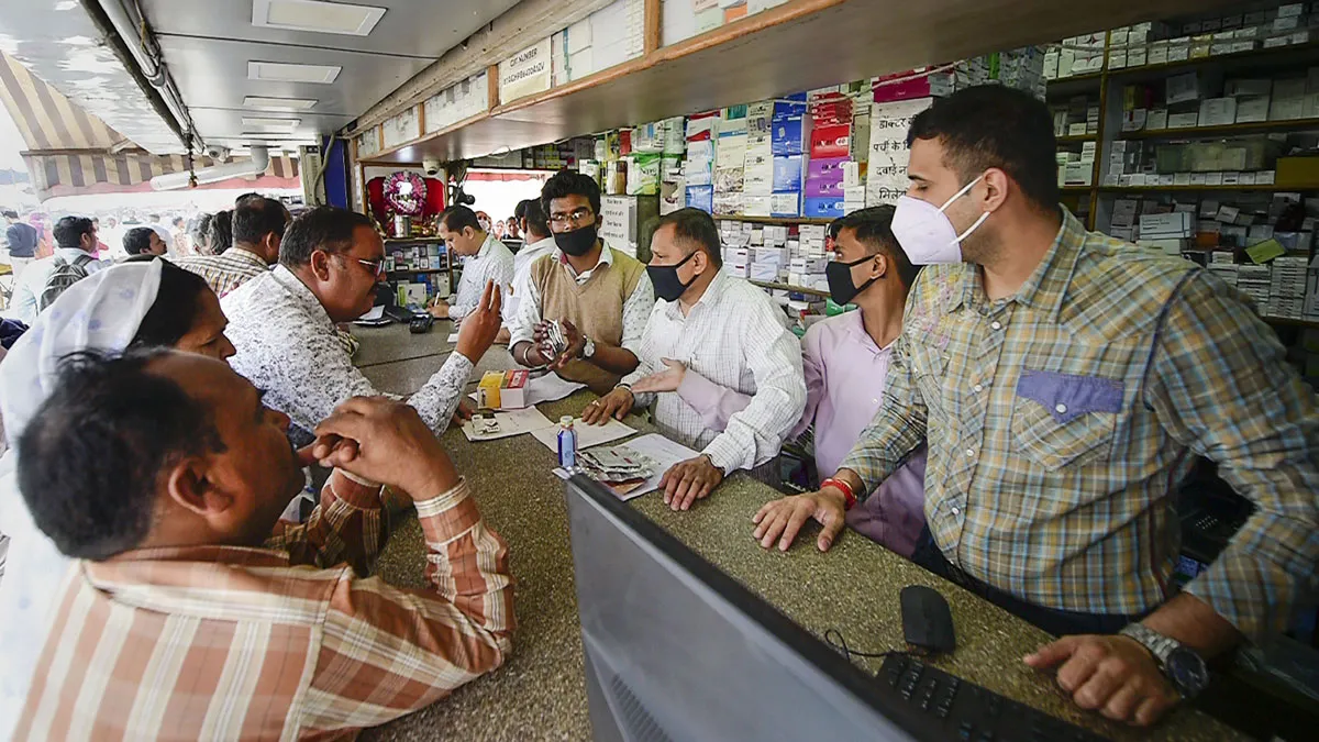 Salesmen at a chemist shop wear protective masks, in wake...- India TV Hindi