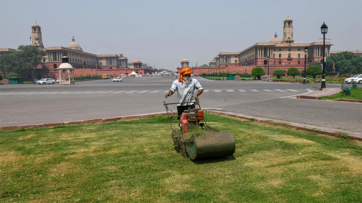 New Delhi: A gardener wearing a face mask mows the lawn at...- India TV Hindi