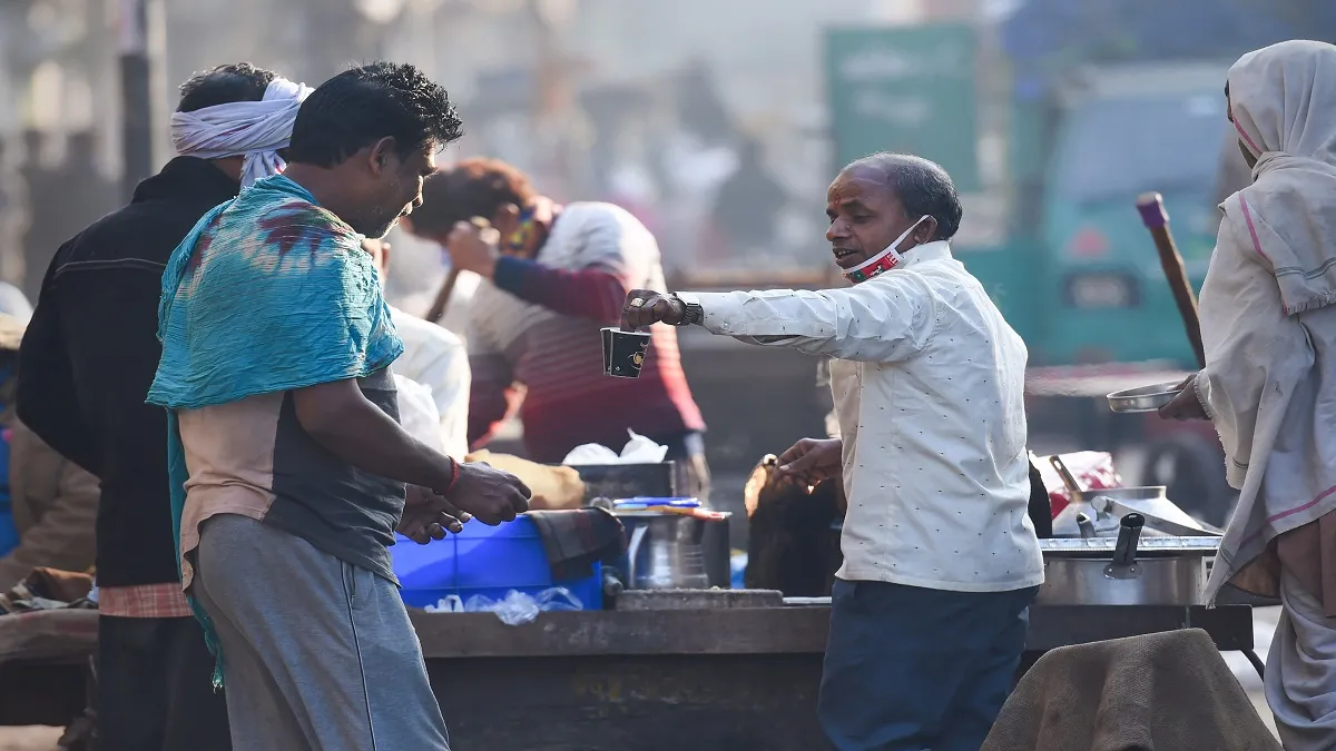 People buy tea from a roadside vendor as temperatures drop in the city, in New Delhi.- India TV Hindi