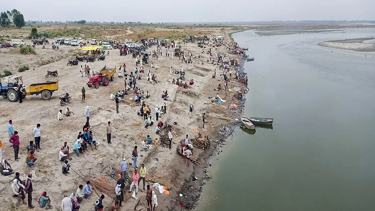 Relatives and family wait to cremate on the banks of River Ganga, in Unnao on Thursday.- India TV Hindi