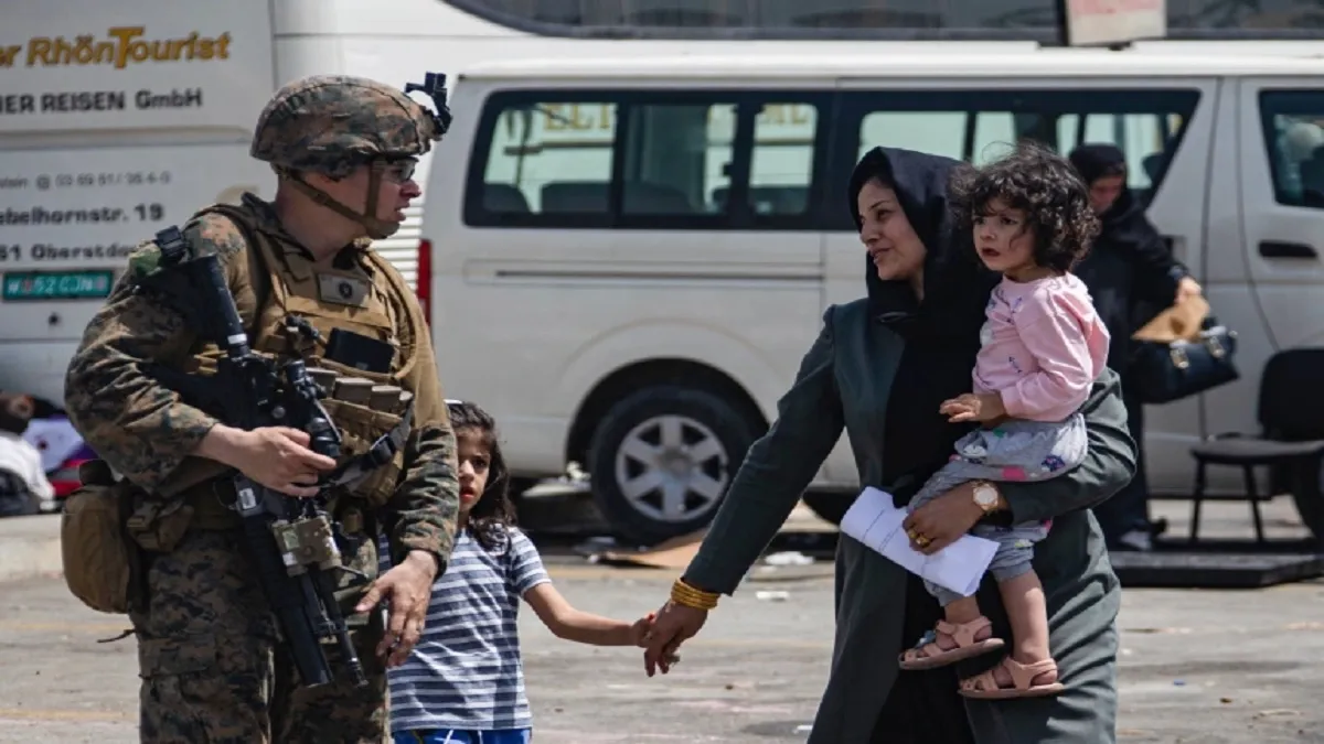 A US Marine escorts evacuees at Hamid Karzai International Airport, in Kabul, Afghanistan- India TV Hindi