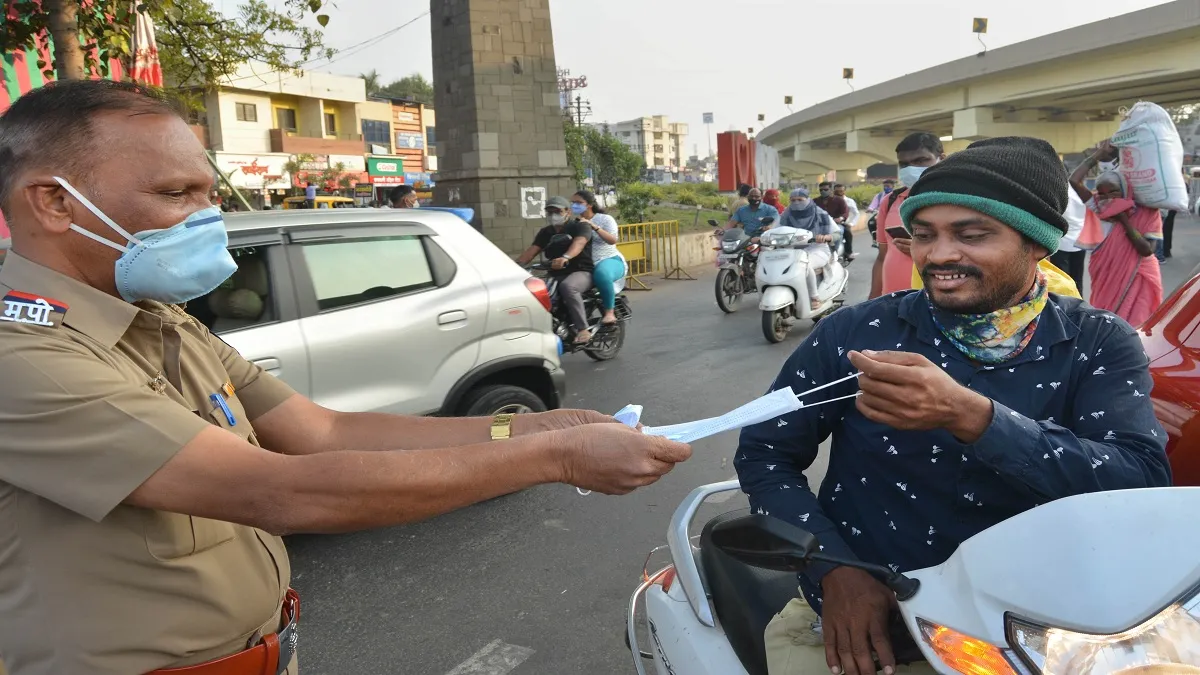 A traffic police officer gives a face mask to a commuter after charging a fine for not wearing one, - India TV Hindi