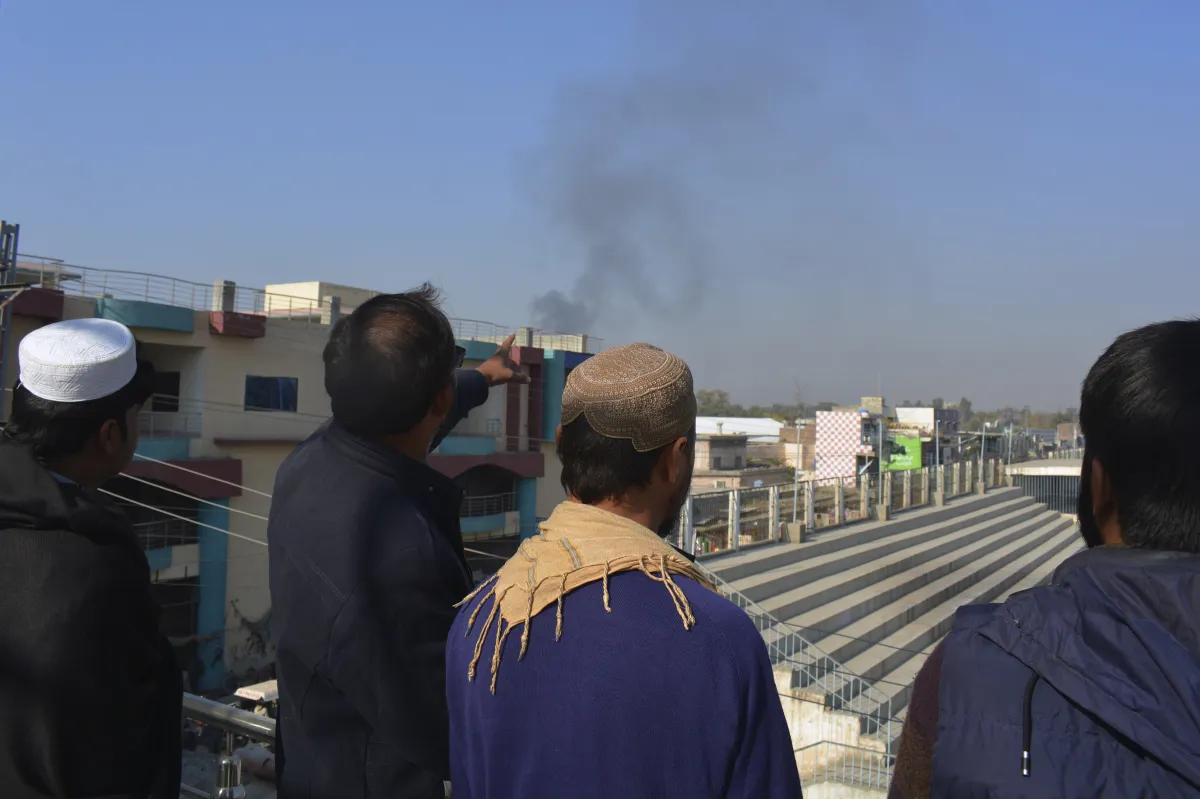 पाकिस्तानी सेना के ऑपरेशन के बाद घटनास्थल से उठते धुएं को देखते लोग- India TV Hindi