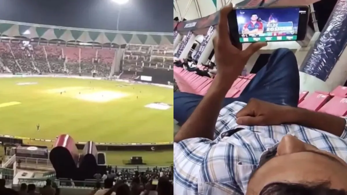 स्टेडियम में बैठकर फोन में मैच देखता हुआ शख्स- India TV Hindi