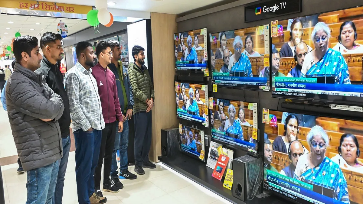 टीवी की दुकान पर रविवार को बजट भाषण सुनते लोग।- India TV Paisa