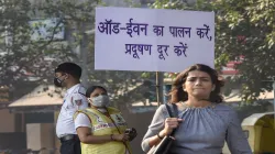 Civil Defence volunteer wearing a mask displays a placard asking people to obey the odd-even rule, i- India TV Paisa