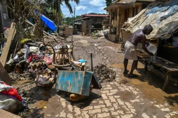 <p>A man cleans up his house after flood water subsided, in...- India TV Hindi