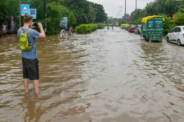 <p>A person takes a photo while standing on a waterlogged...- India TV Hindi