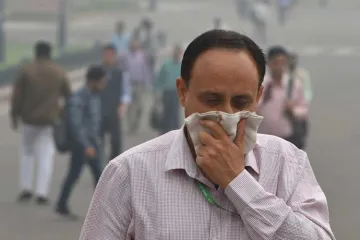 <p>A pedestrian covers his face with a handkerchief for...- India TV Hindi