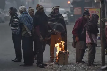<p>People gather around a makeshift bonfire to warm...- India TV Hindi