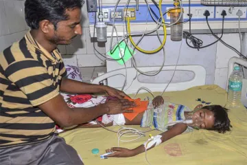 A man takes care of a child suffering from Acute Encephalitis Syndrome (AES) at a hospital in Muzaff- India TV Hindi