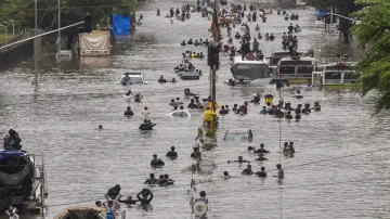 People wade through a flooded railway tracks during heavy rain, in Mumbai.- India TV Hindi