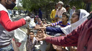 <p>A volunteer distributes food among homeless people near...- India TV Hindi