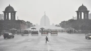 A man runs for cover as heavy rains accompanied by hailstorm lashed parts of the national capital, a- India TV Hindi