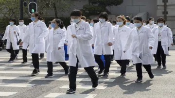 <p>Wuhan: Medical workers from Beijing walk near a park...- India TV Hindi