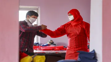 <p>Jammu: A volunteer helps a civil servant to wear a...- India TV Hindi
