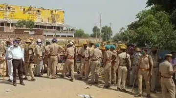 Police personnel stand guard at the entrance of Boolgarhi village where the family of 19-year-old Da- India TV Hindi