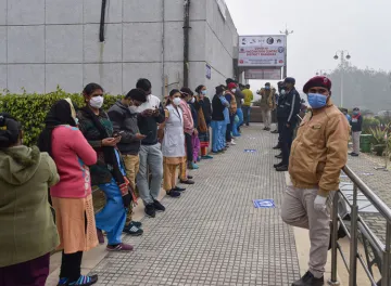 <p>Health workers stand in a queue as they wait for their...- India TV Hindi