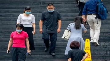 People wearing face masks to protect against COVID-19 walk down stairs at a shopping and office comp- India TV Hindi