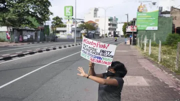 A Sri Lankan woman protests holding a placard during a curfew in Colombo, Sri Lanka, Sunday. - India TV Hindi