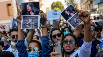 Woman hold up drawings of Iranian Mahsa Amini as they shout slogans during a protest against her dea- India TV Hindi