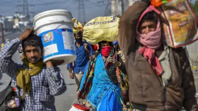 <p>A group of migrants carry their belongings as they walk...- India TV Hindi