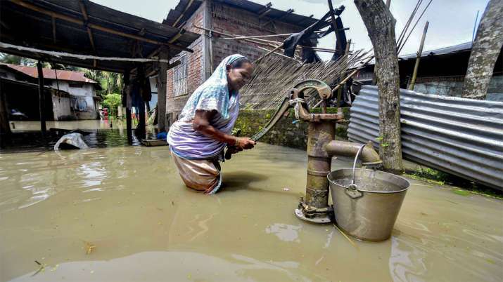 असम के कामरूप में हैंड पंप से पानी भरती महिला 