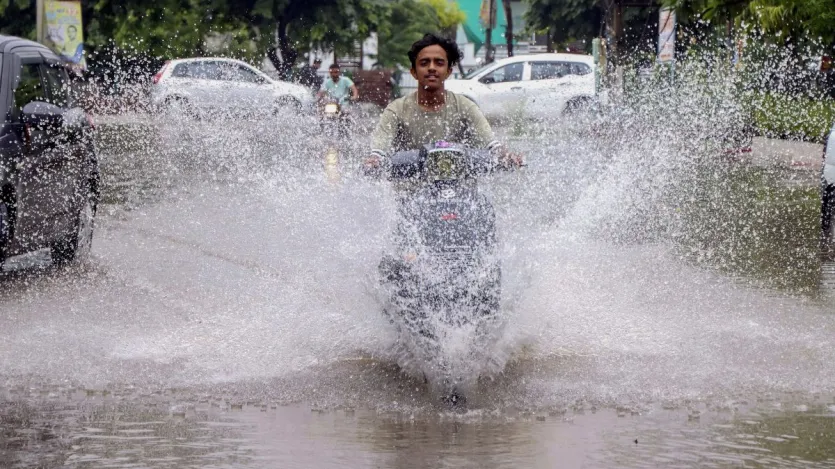 हरियाणा के रोहतक में भारी बारिश के बाद जलभराव वाली सड़क से गुजरता एक यात्री।