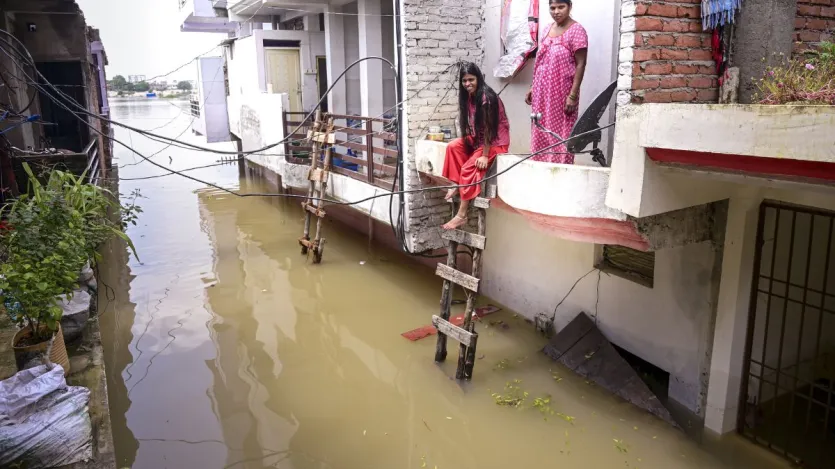 प्रयागराज के छोटा बघारा में गंगा नदी का जल स्तर बढ़ने पर बाढ़ का पानी घरों में घुस गया है। एनडीआरएफ की टीमें राहत बचाव कार्य में जुटी हैं। महिलाएं छत से नीचे आने के लिए सीढ़ियों का इस्तेमाल कर रही हैं।
