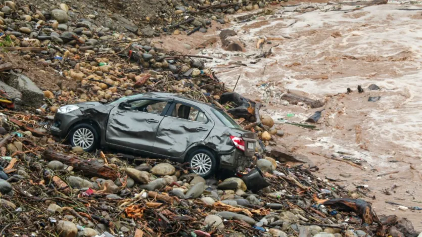 जम्मू में भारी बारिश के कारण तवी नदी का जलस्तर बढ़ने के बीच एक पुल का एक हिस्सा बह जाने के बाद मलबे के बीच क्षतिग्रस्त कार पड़ी है। 