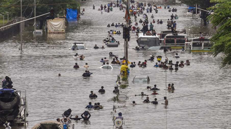 People wade through a flooded railway tracks during heavy rain, in Mumbai. People wade through a flooded railway tracks during heavy rain, in Mumbai.- India TV Hindi