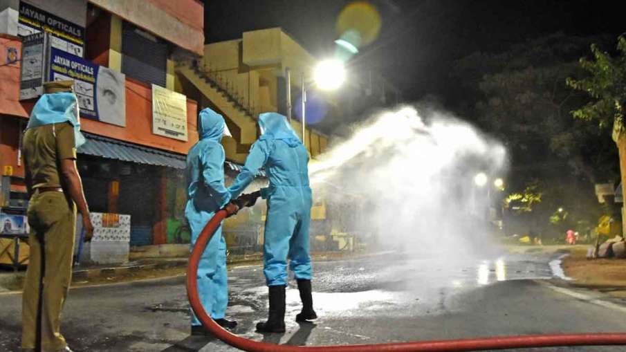 Health workers spray disinfectant on a street during the... Health workers spray disinfectant on a street during the...- India TV Hindi