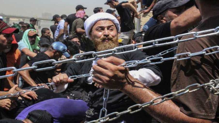 Iraqi protesters use chains to try to remove concrete barriers on their way to the Parliament buildi- India TV Hindi News