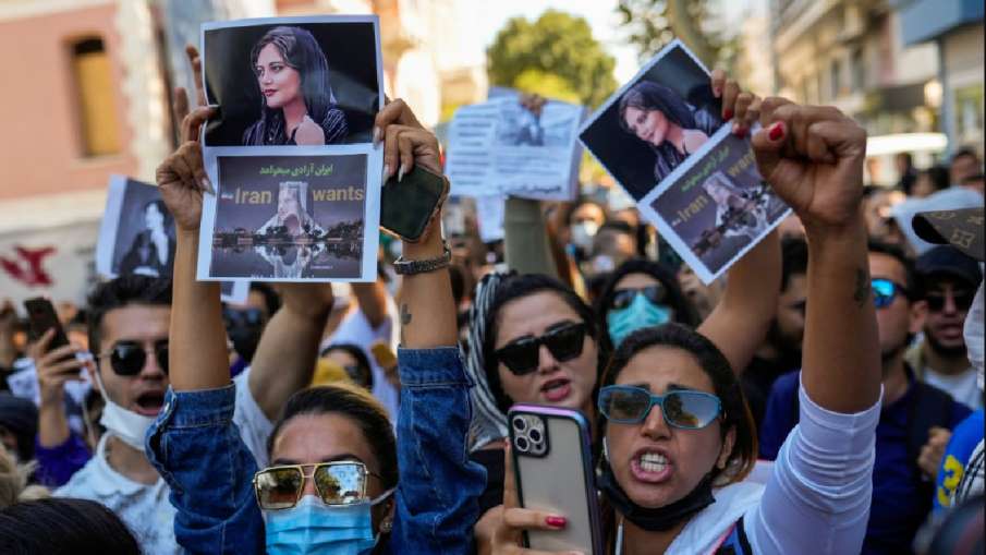 Woman hold up drawings of Iranian Mahsa Amini as they shout slogans during a protest against her dea- India TV Hindi News